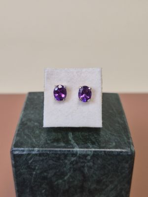 une paire de boucles d'oreilles en amethorate posées sur un bloc de marbre