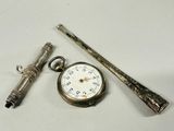 a silver pocket watch, a pen, and a pocket watch on a table