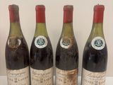quatre bouteilles de vin sont alignées sur une surface blanche