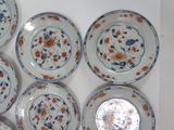 six blue and white plates with red and blue designs are arranged on a white surface