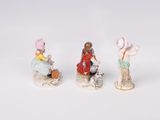 three figurines of a woman, a man, and a dog on a white surface
