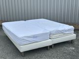 a white bed with two mattresses on it in front of a building