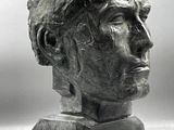 sculpture représentant une tête d'homme sur un socle, avec un fond gris
