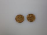 two gold coins sitting side by side on a white surface