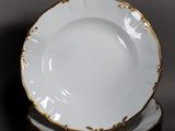 four white and gold plates stacked on top of each other