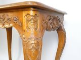 une table en bois dont le plateau est sculpté, sur fond blanc