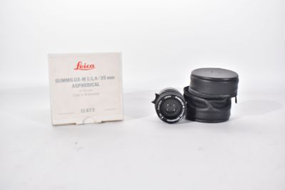 an old black camera with a box and lens on a white surface