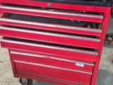 une boîte à outils rouge avec des outils posés dessus, dans un garage