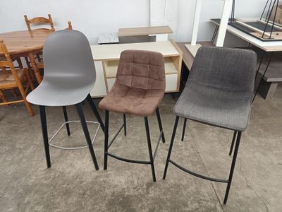 trois chaises et une table dans une pièce où l'on aperçoit, en arrière-plan, une table et des chaises