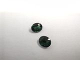 a pair of green tourmaline gems on a white surface