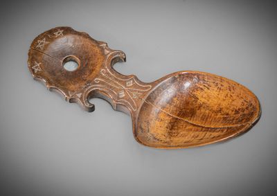 an old wooden spoon with a carved handle on a gray surface
