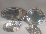 trois plats en métal argenté et un miroir posés sur une table