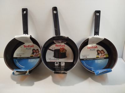 three frying pans sitting on top of a white counter top