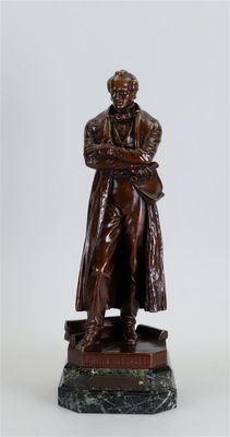 statue d'un homme en manteau et chapeau, les bras croisés