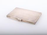 an old silver cigarette case sitting on top of a white table