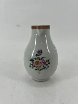 a small white vase with a floral design on it