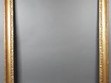 a gold framed mirror on a gray wall with a black background
