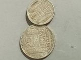 two silver coins sitting next to each other on a white surface