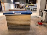 un plan de travail bleu posé dans un entrepôt, à côté d'un seau rouge