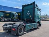 a green semi truck parked in front of a blue building
