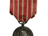 une vieille médaille entourée d'un ruban à rayures rouges et blanches