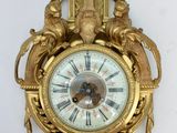 a gold clock hanging on the wall with a clock on it