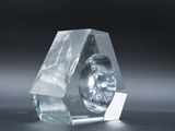 a glass sculpture of a diamond shaped object on a black surface