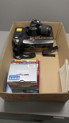 une boîte remplie de livres et un appareil photo posé sur une table
