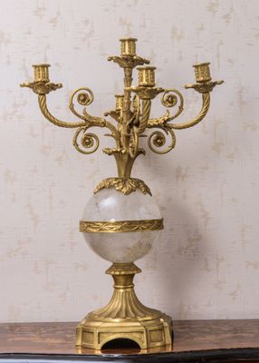 un candélabre en or surmonté d'une boule de marbre