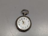 une montre de poche en argent posée sur une table avec un fond blanc
