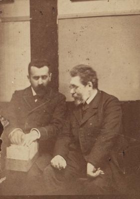trois hommes assis à une table, dont l'un est en train de couper un gâteau
