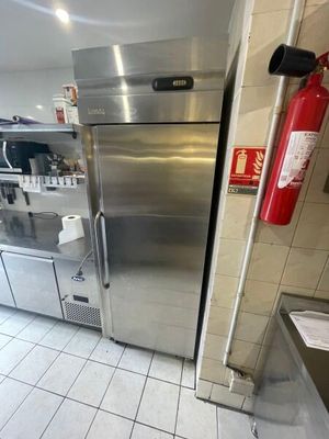 un réfrigérateur en acier inoxydable dans une cuisine équipée d'un extincteur