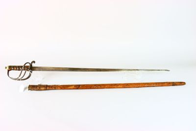 une vieille épée à la poignée en bois posée sur une surface blanche