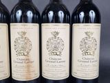 four bottles of red wine are lined up on a table