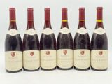 six bouteilles de vin sont alignées sur une surface blanche