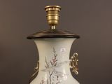 a white vase with a gold handle on a table