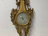a gold clock on the wall with a bird on it