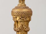a gold vase with a bird on top of it