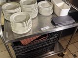 many plates and bowls on a metal cart in the kitchen