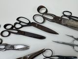 many pairs of scissors sitting on a white surface