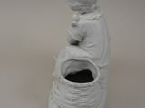 a white figurine of a boy sitting on top of a basket