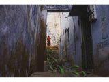 a man walking down a narrow alley way with graffiti on the walls