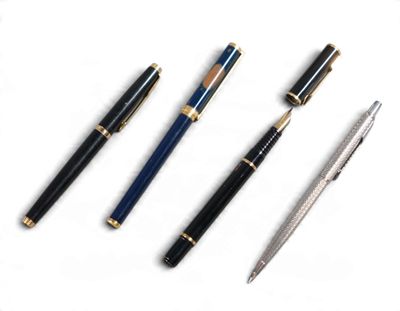 trois stylos et une paire de ciseaux posés sur une surface blanche