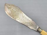 a silver knife with a yellow handle on a gray surface