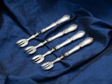 a set of five silverplated forks and spoons on a blue cloth