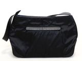 le sac noir est posé sur une surface blanche et est muni d'une bandoulière noire