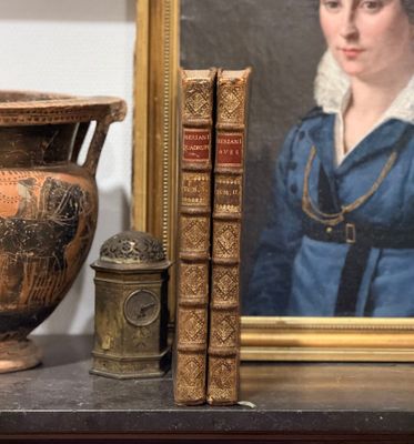 une photo d'une femme en robe bleue, à côté d'un vase et de livres