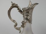 a silver and white vase with a handle on a table