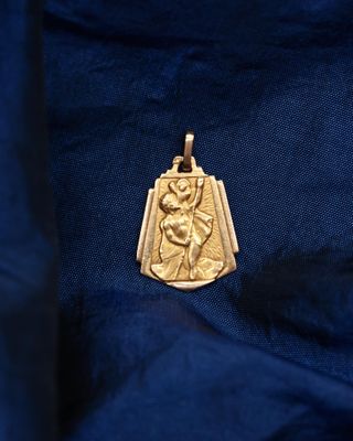 a gold pendant with an image of a woman holding a child