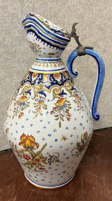un vase muni d'une anse bleue posé sur une table en bois